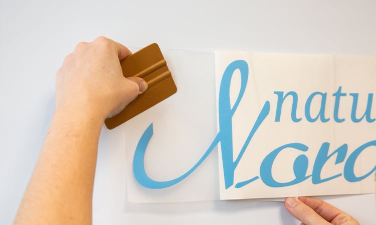 Klebebuchstaben werden mit einem Spatel an der Wand angebracht. Klebebuchstaben werden mit einem Spatel an der Wand angebracht.