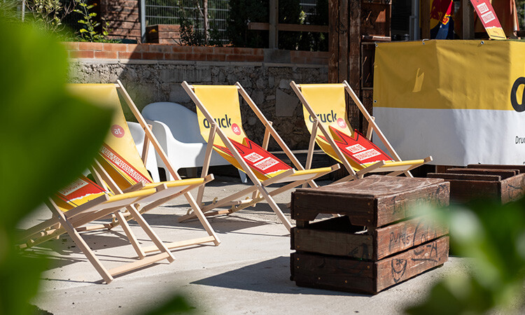 Gebrandete Liegestühle stehen in einer Reihe hinter einer Holzkiste als Tisch Gebrandete Liegestühle stehen in einer Reihe hinter einer Holzkiste als Tisch