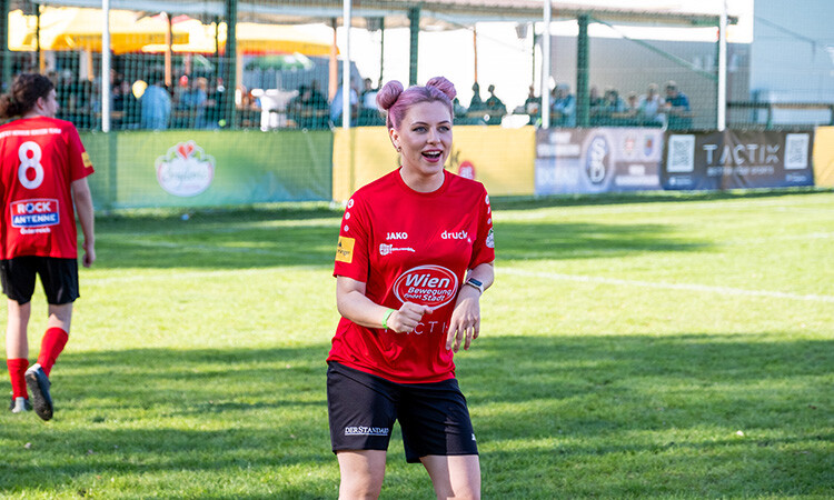 Eine der Fußballspielerinnen freut sich und steht lachend auf dem Fußballplatz Eine der Fußballspielerinnen freut sich und steht lachend auf dem Fußballplatz