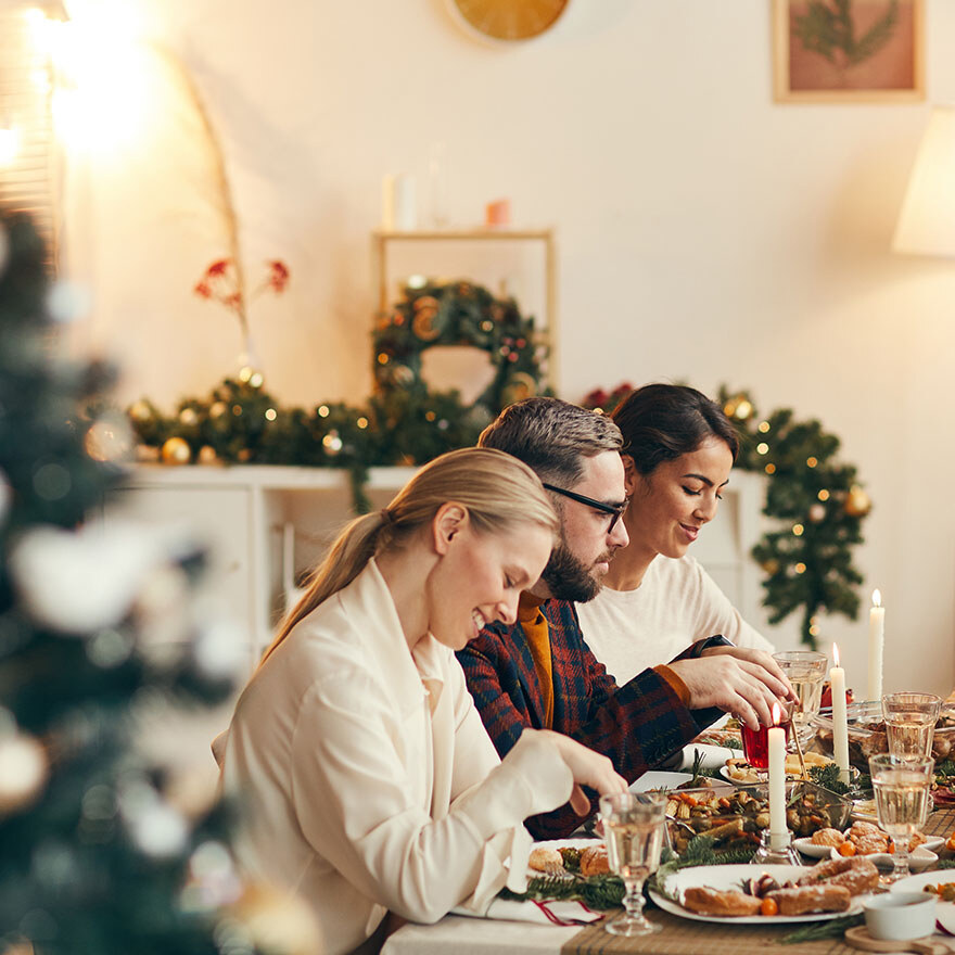 Drei Freunde sitzen gemeinsam am gedeckten Weihnachtstisch