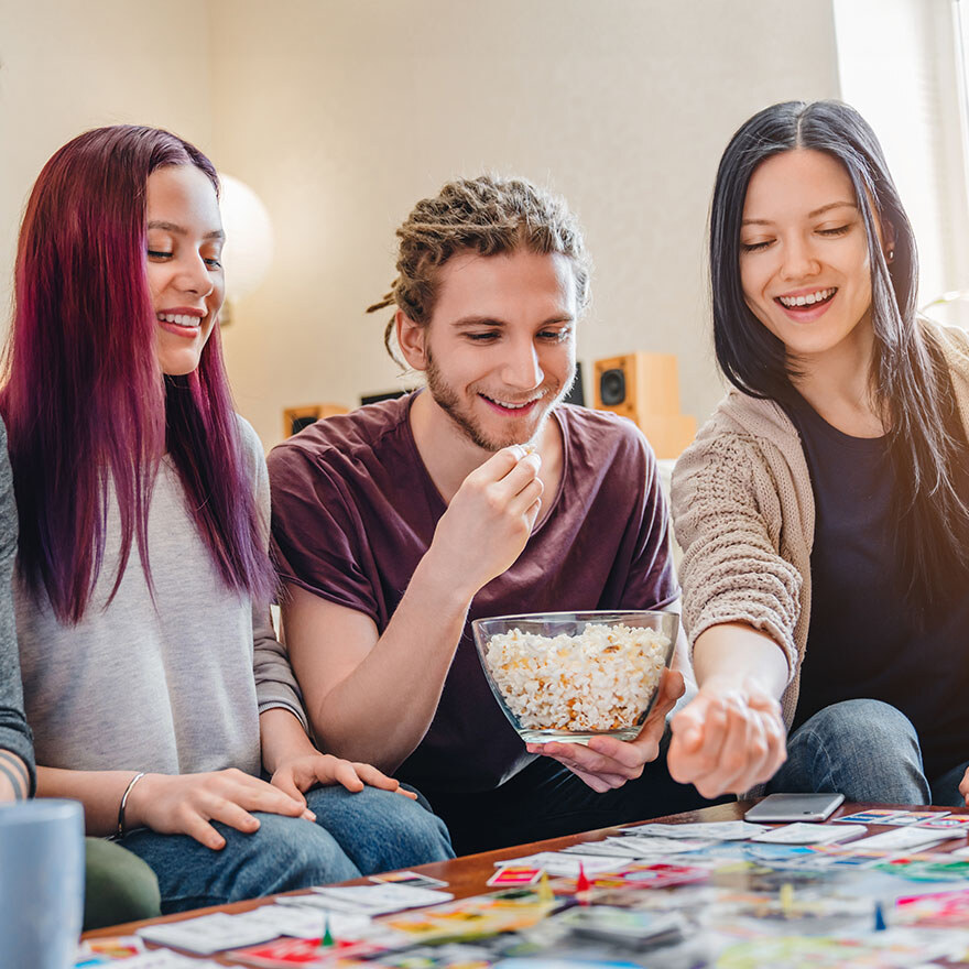 Drei Personen sitzen am Tisch und spielen ein Spiel