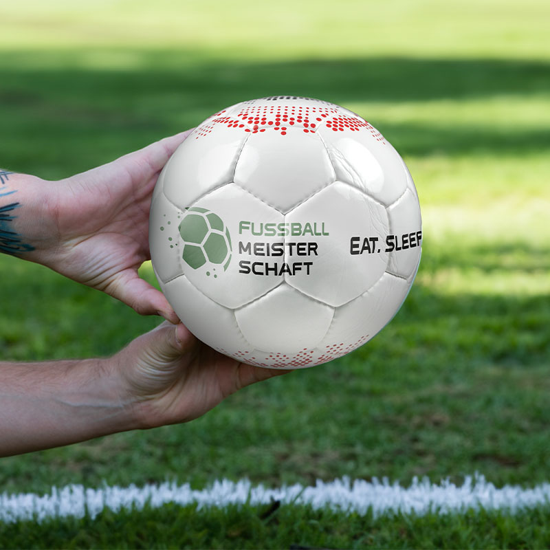 Zwei Hände halten einen Fussball in der Hand.