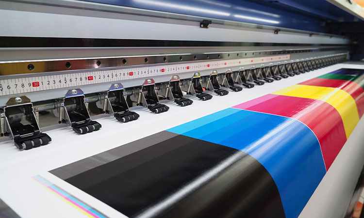 Ein Testdruck mit kräftigen Farben verlässt die Druckmaschine.