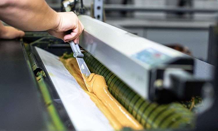Farbe wird mit einem Spatel auf eine Rollenoffsetdruckmaschine aufgetragen.