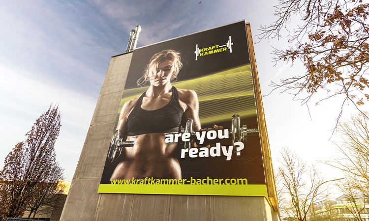 Ein großes Plakat mit Werbung für ein Fitnessstudio an einer Gebäudewand