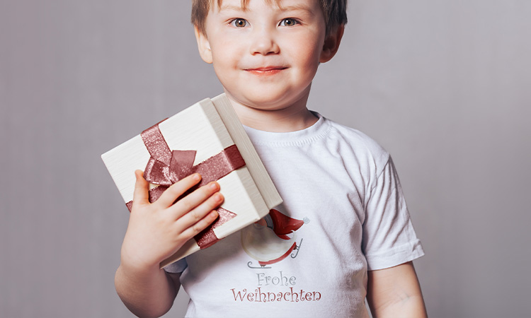 Kind mit individuell bedrucktem T-Shirt und einem Geschenk in der Hand