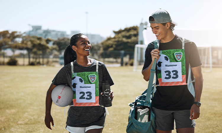 Zwei Fußballspieler gehen mit Startnummern und einer Sporttasche vom Feld Zwei Fußballspieler gehen mit Startnummern und einer Sporttasche vom Feld