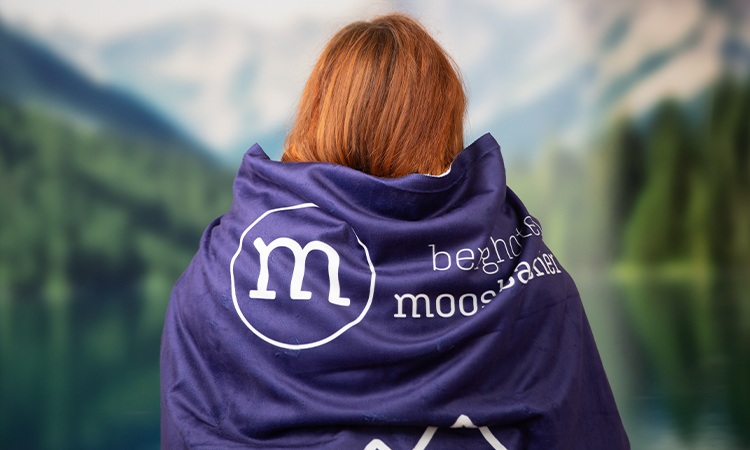 Frau mit einer bedruckten Decke um die Schultern schaut in die Natur Frau mit einer bedruckten Decke um die Schultern schaut in die Natur