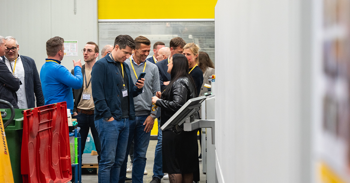 Mehrere Personen stehen in der Produktionshalle und unterhalten sich Mehrere Personen stehen in der Produktionshalle und unterhalten sich