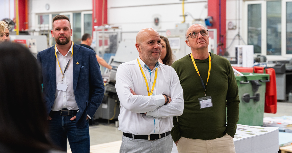 Mehrere Männer stehen in der Produktionshalle und betrachten die Maschinen Mehrere Männer stehen in der Produktionshalle und betrachten die Maschinen